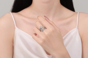 Macro detail of leaf-shaped silver ring with adjustable open band on model's hand