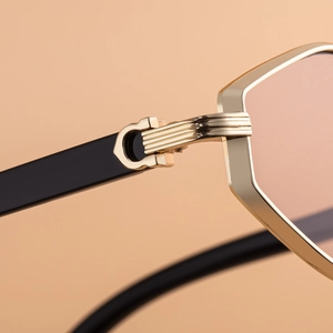 Close-up of golden polygon metal frame with pink lenses and C-shape hinge detail