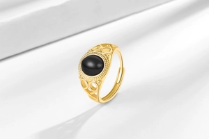 Detailed view of vintage gold ring with oval black onyx and hollow floral carvings