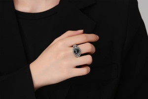 Detailed close-up of retro silver ring with oval black agate on model wearing black suit