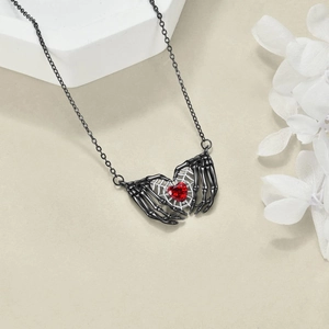 Gothic style necklace featuring black skeleton hands holding a dark red heart pendant