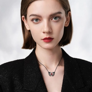 Close-up of gothic skeleton hand pendant clutching a dark red heart gem on a black chain