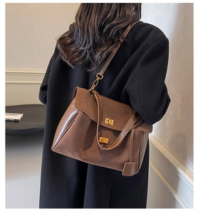 Détail d'un sac cabas en cuir et daim marron avec boucles en métal doré sur un mannequin