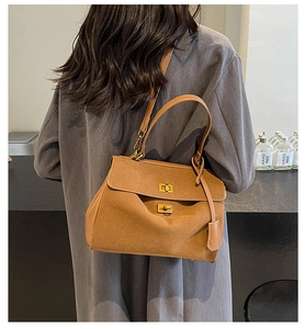 Détail du sac à main en daim caramel avec doubles fermoirs rotatifs dorés