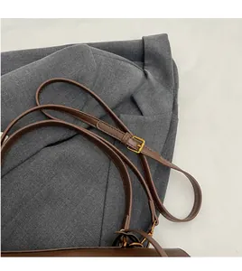Détail de la bandoulière réglable en daim marron avec boucle dorée sur tissu