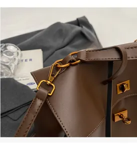 Détails du fermoir doré rotatif et de la texture en daim mat d'un sac cabas marron