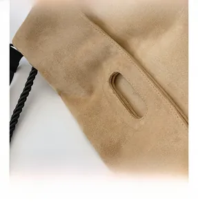 Detail of a minimalist suede tote bag featuring oval cutout handles and thick braided strap