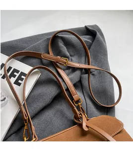 Détail du sac en cuir dépoli marron foncé avec bandoulière réglable et fermoirs dorés