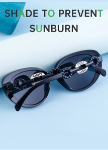 Close-up of black oval sunglasses with distinctive gold and black chain-link temple design