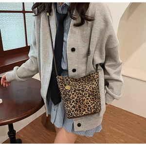 Detail of leopard print bucket bag with leather strap and gold charm in home setting