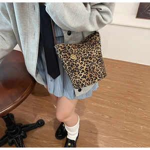 Detail view of leopard print tote bag featuring a gold rose charm and metal chain strap