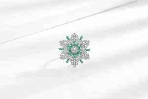 Detailed macro view of rotatable snowflake ring with emerald green square gemstones