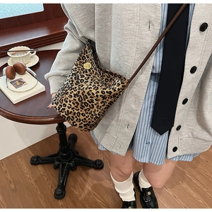 Detail of leopard print bucket bag with vintage gold charm and brown leather strap