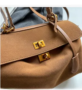 Gros plan du fermoir rotatif en bronze et de la texture en cuir suédé marron du sac