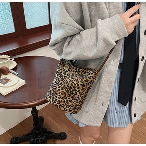 Close-up of leopard print tote bag featuring a delicate gold floral metal pendant detail