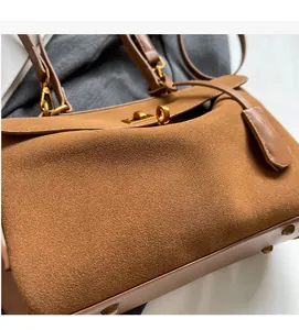 Détail de la texture en daim marron et du fermoir en métal doré sur le sac à main