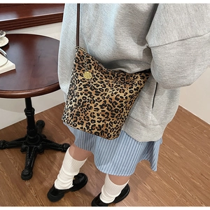 Detail of leopard print bucket bag with brown leather strap and golden floral charm
