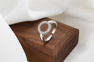 Macro detail of adjustable silver ring with sparkling white zircon circle on wood stand