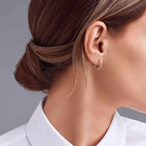 Detail of gold hoop earrings with zircon pavé stones worn by a model in a lifestyle shot