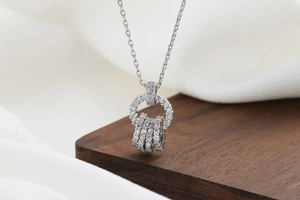Detailed view of silver zircon necklace with multi-ring pendant on rustic wood background