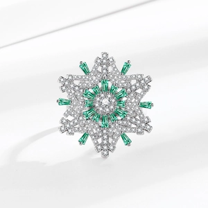 Rotating snowflake ring with green and white gems on a minimalist white background
