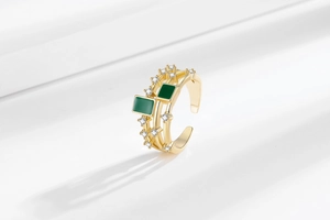 Macro detail of gold layered ring featuring green resin stones and paved white zircons