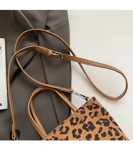 Détail de la bandoulière réglable en cuir marron avec boucle argentée sur sac léopard