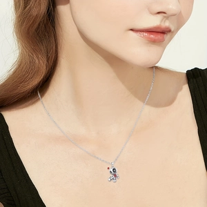 Gothic voodoo doll necklace with red heart detail worn on a model against white background
