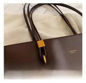 Close-up of premium golden metal hardware and ring buckle on a brown leather tote bag