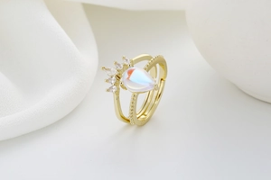 Macro shot of double-layer gold ring with opal teardrop stone and crown-shaped zircons