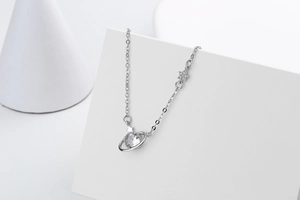 Macro detail of silver planet pendant with crystal stone and orbit ring on cross chain