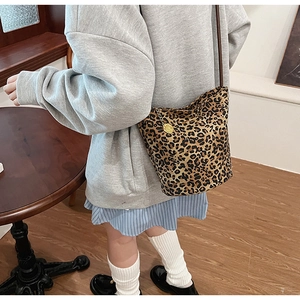 Close-up of leopard print tote bag with gold charm detail and brown leather strap