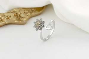 Macro shot of silver rotating sunflower ring with gold center and镂空 heart design