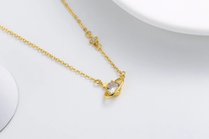 Macro detail of gold planet necklace with a large clear zircon and a small star charm