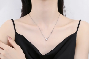 Close-up of a silver Saturn planet necklace with a brilliant zircon stone on a model