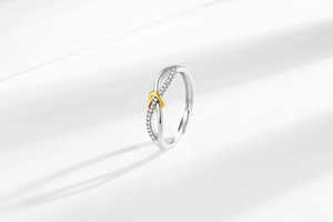 Detail of silver infinity ring with gold heart accent and zircon stones on white background