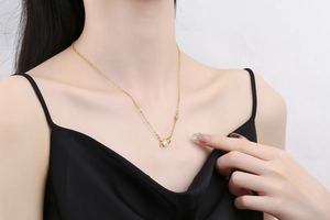 Detail shot of a dainty gold planet necklace with rhinestones worn on a model's collarbone