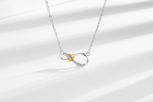 Macro shot of silver infinity and gold heart pendant necklace with shimmering crystals