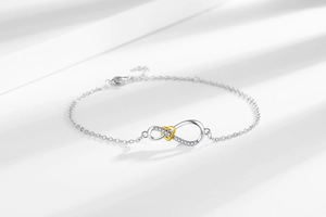 Detail of silver infinity symbol and gold heart bracelet with sparkling zircon stones