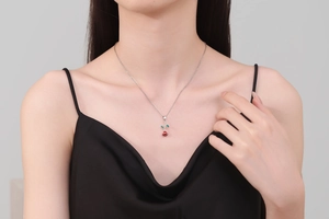 Detailed view of an elegant red rose pendant necklace worn on a silver-toned delicate chain