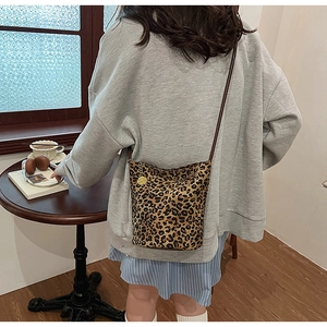 Detail of leopard print tote bag with brown leather strap and golden charm pendant