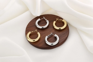 Detailed view of polished gold and silver hoop earrings on elegant silk background