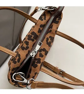 Détail du zip en métal argenté et de l'anse en cuir marron sur le sac seau à motif léopard