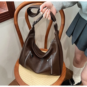 Detail of dark brown PU leather tote with vertical silver zippers on wooden chair