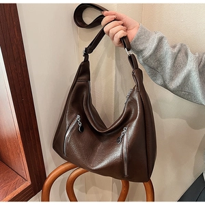 Detail of dark brown faux leather hobo bag with dual decorative front zippers and wide strap