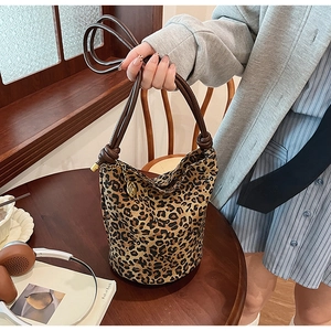 Detail of leopard print bucket bag with woven knot handle and metal chain accessory