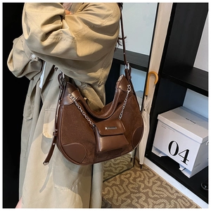 Detail of coffee brown half-moon shoulder bag with metal chain and mini pouch accessory