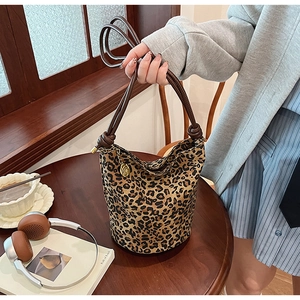 Detail of vintage leopard print bucket bag with brown leather handles and gold pendant