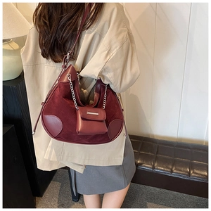 Detail of burgundy patchwork bucket bag with suede texture and silver chain charm