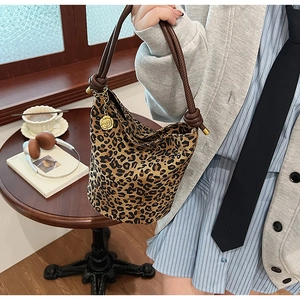 Detail of vintage leopard print bucket bag with woven rope handle and rose gold pendant